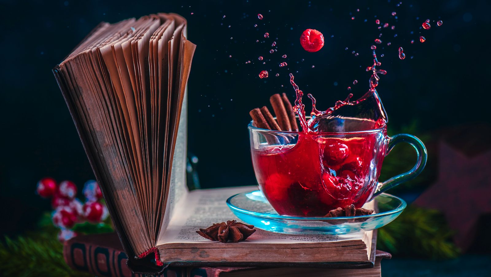 Red berry tea on a stack of books with a dynamic splash. Winter hot drink on a dark background with copy space